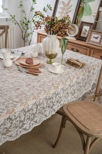 Detailed view of white floral lace tablecloth featuring intricate hollow embroidery patterns