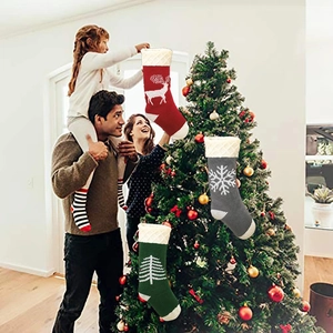 Three knitted Christmas stockings with reindeer, snowflake and tree patterns for holidays