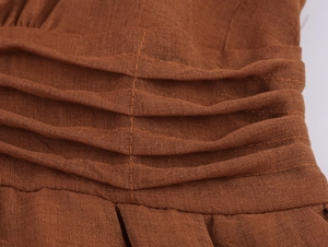 Macro detail of the ruched waist design and texture on a brown linen blend dress