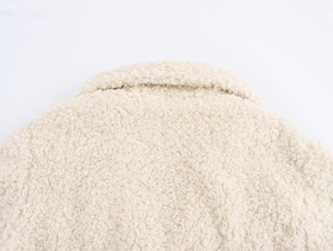 Detailed close-up of cream white faux fur lamb wool texture on collar and back of coat