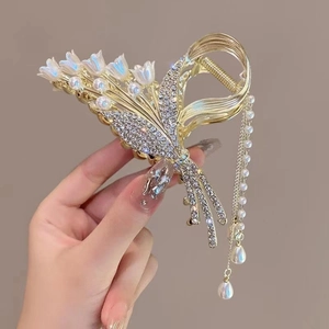 Detail van lelietje-van-dalen haarklem met fonkelende strass en parel kwastjes