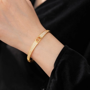Close-up of gold-plated D-letter bangle with white zircons worn on model's wrist