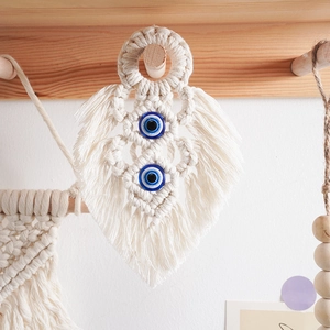 Detail of macrame leaf wall hanging with blue evil eye beads and soft cotton fringe