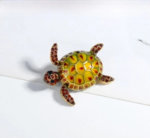 Detail of a turtle brooch featuring green enamel shell and sparkling red rhinestones