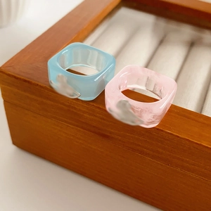 Detail of square resin rings in pink and blue with silver bird metal ornaments
