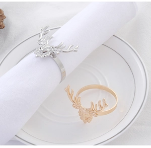 Detail shot of gold and silver reindeer napkin rings on white fabric and plate
