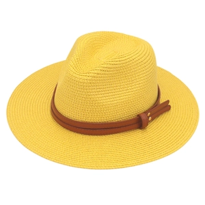 Close-up of yellow straw fedora with a brown faux leather band and gold metal rivets