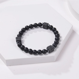 Matte black stone beaded bracelet with volcanic rock on a white geometric stand
