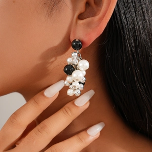 Long beaded drop earrings with black beads and faux pearls worn by a female model