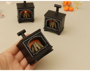 Macro view of a hand holding a miniature light-up dollhouse fireplace model in black