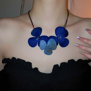 Close-up of a blue resin clover flower necklace pendant on a brunette model