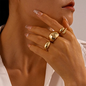 Close-up of golden liquid metal style rings with mirror finish worn by a fashion model