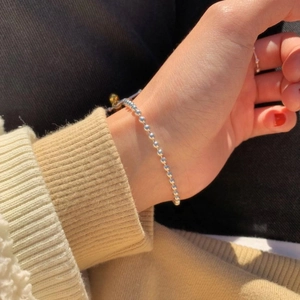 Close-up of minimalist S925 sterling silver beaded heart bracelet on a woman's wrist