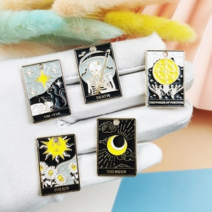 Five-piece tarot enamel charms featuring Sun and Moon designs held in a gloved hand
