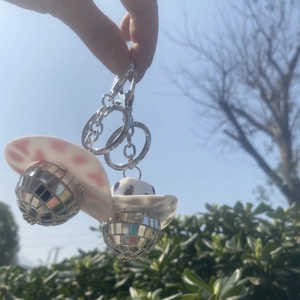 Disco-Kugel-Schlüsselanhänger mit Cowboyhüten vor blauem Himmel und grünen Büschen