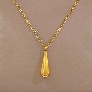 Detail eines goldenen Tropfenanhängers an einer eleganten Halskette aus Titanstahl