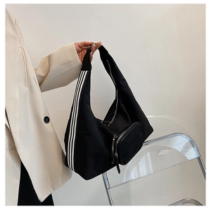Detail of black nylon shoulder bag featuring white stripes and front zipper pocket