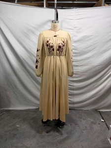 Detail of heavy embroidery and hollow-out neckline on beige long-sleeved dress