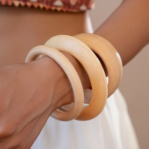 Macro shot of three stacked resin wood grain bangles with natural texture and warm finish
