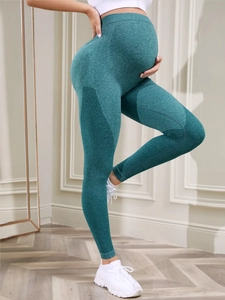 Close-up of seamless knit maternity yoga leggings in dark green with breathable side mesh
