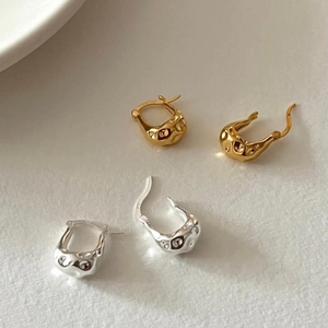 Irregular lava style stud earrings in gold and silver finish on neutral background
