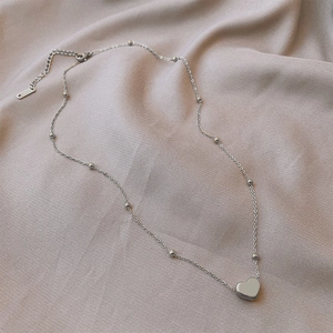 Macro shot of silver titanium heart pendant with small metal beads and S.STEEL hallmark