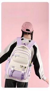 Detailed back view of a purple and beige student backpack with multi-pockets and cute patch