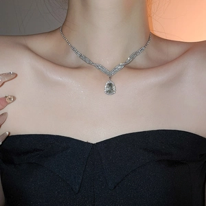 Detailed view of a silver V-shaped necklace with a sparkling teardrop diamond pendant