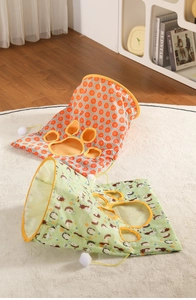 Close-up of foldable cat tunnels with grapefruit and hedgehog patterns and plush balls