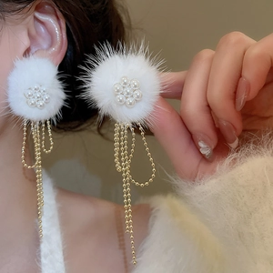 Detail of elegant white pompom earrings with pearl flower clusters and gold fringe tassels