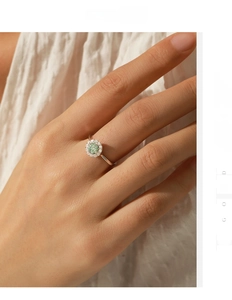 Detailed view of an S925 sterling silver ring with a green moissanite halo on a finger