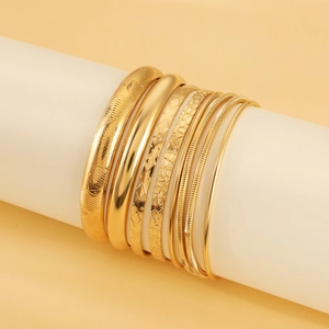 Detail of 8-piece gold bracelet set showing matte, polished, and textured alloy finishes