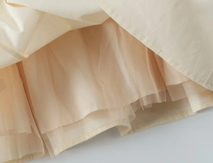 Close-up of double-layered structure showing mesh fabric and fine stitching on beige dress
