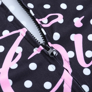Close-up of black hoodie zipper on polka dot fabric with pink abstract print