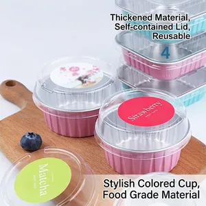 Pink and blue aluminum foil baking cups with clear lids on a wooden tray