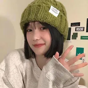 Women's chunky knit beanie in grass green featuring a white side woven label for winter warmth