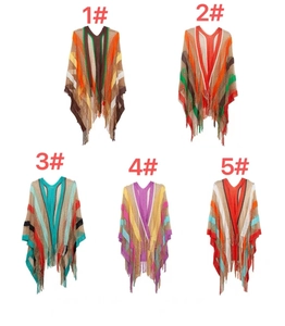 Flat lay of five colorful striped knit ponchos with v-neck and tassels on white background