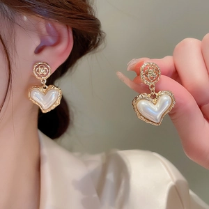 Elegant gold heart pearl drop earrings with rose embossments worn on the earlobe