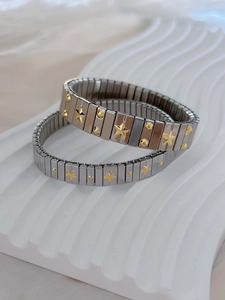 Detail of silver elastic link bracelets with gold star patterns on a white stand