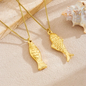 Gold-plated stainless steel koi fish pendant necklace with box chain on sandy surface