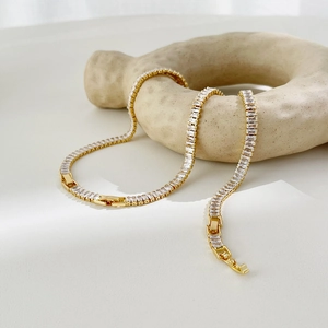 18k gold plated tennis necklace with baguette cut cubic zirconia on ceramic ring stand
