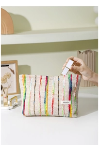 Détail d'une trousse à maquillage tissée avec broderies colorées et logo H&R BAG