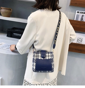 Detail of tweed bucket bag with blue leather trim and geometric patterned shoulder strap
