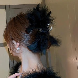 Detail of black feather hair claw clip with satin bow on a stylish hairstyle
