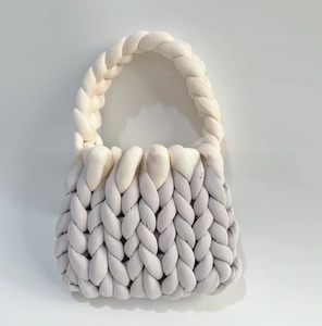 Close-up of dual-tone chunky knit handbag with cream white handle and light grey textured body