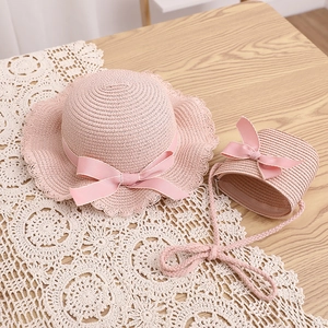 Détail de l'ensemble chapeau et sac en paille rose avec rubans sur bois naturel