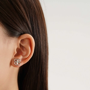 Close-up of a silver clover stud earring with central crystal on a female ear