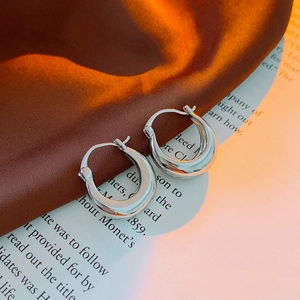 Macro di orecchini a cerchio a U in argento su elegante raso e pagine di libri antichi