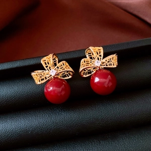 Détails des boucles d'oreilles nœud creux plaquées or 18k avec perles rouges et zircon