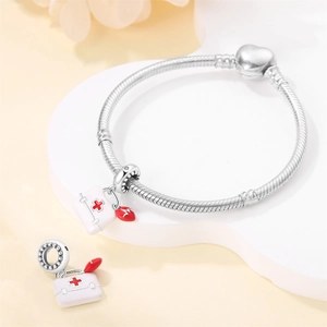 Detailed view of silver medical kit charm with red heart on a snake bone bracelet